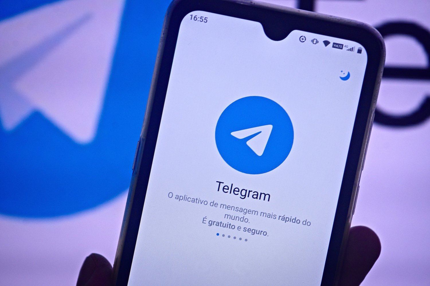 A hand holds a smartphone displaying the Telegram app welcome screen.