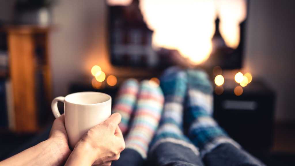 Two people in cosy socks watching TV with a cup of coffee