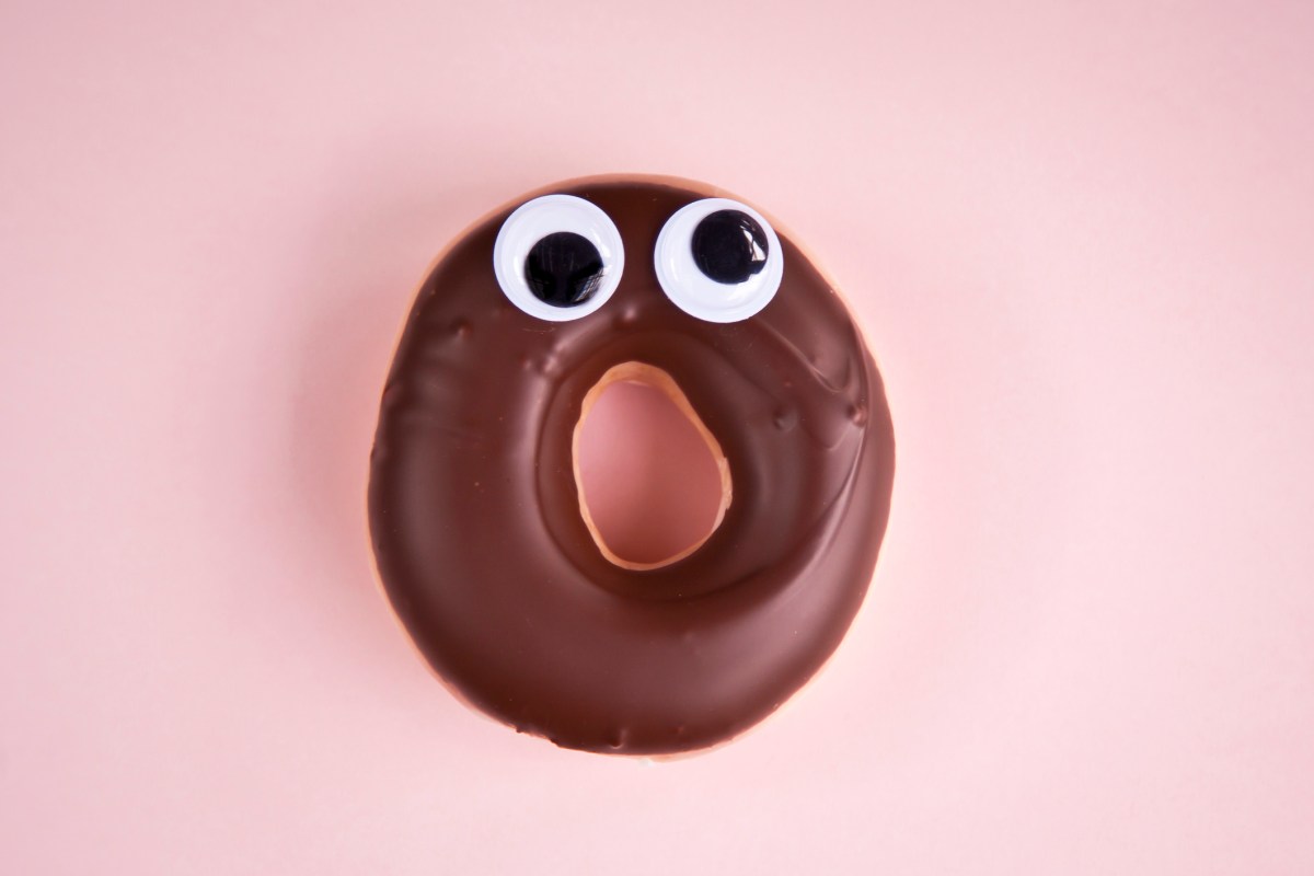 Close-up of a surprised doughnut with chocolate icing and googly eyes.