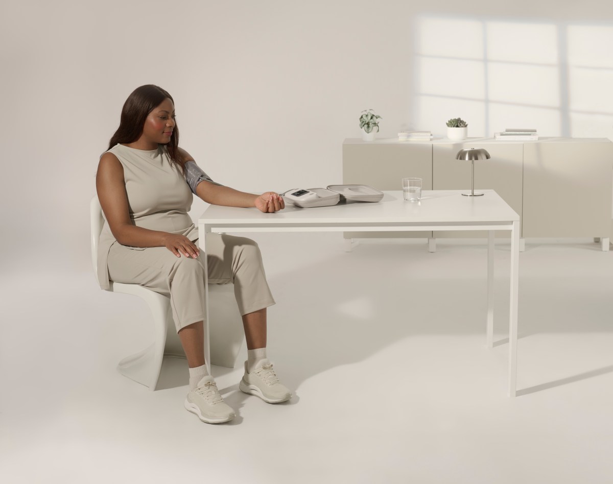 woman sitting at table using Withing blood pressure monitor