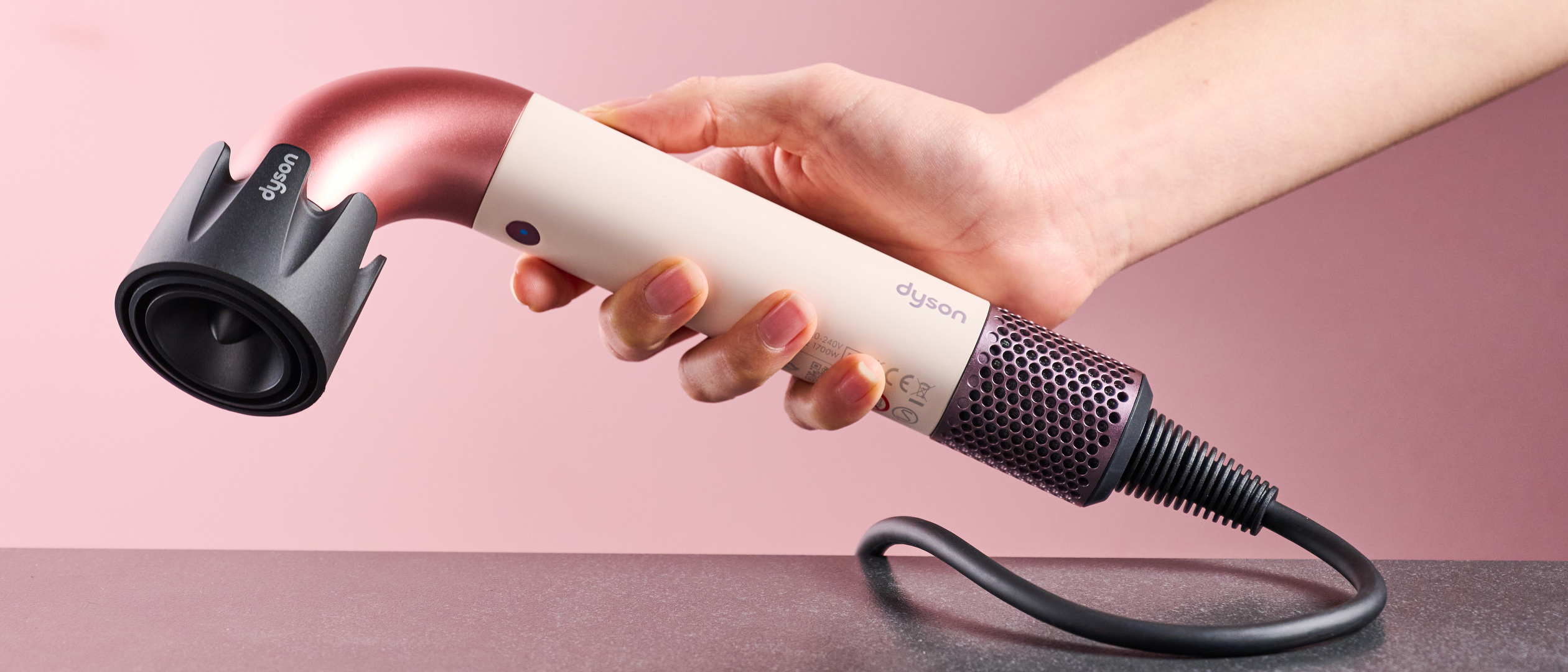 Dyson Supersonic r hair dryer in reviewer's hand, with Powerful air attachment