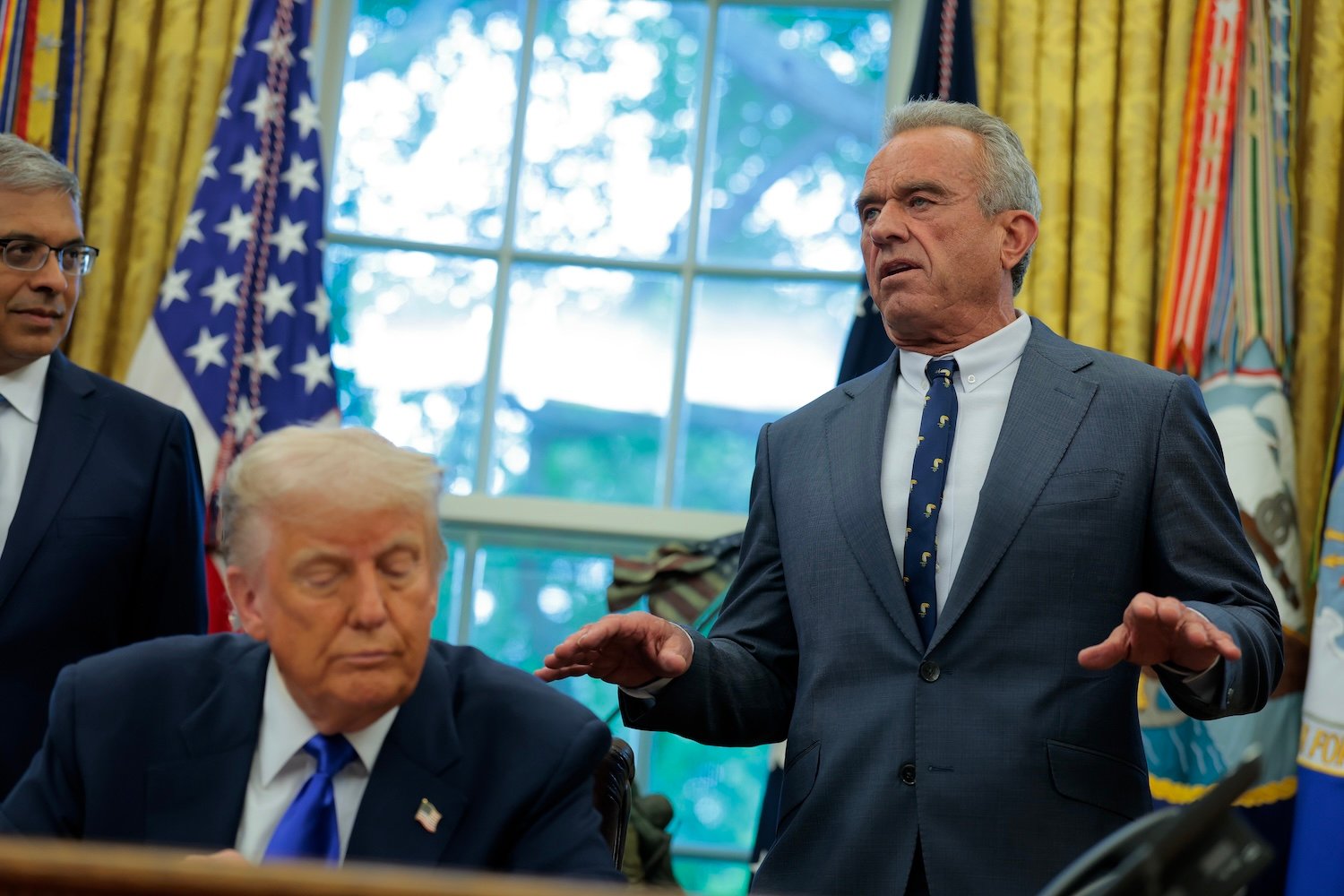 Health and Human Services Secretary Robert F. Kennedy Jr. (R), accompanied by U.S. President Donald Trump and National Institutes of Health Director Jayanta Bhattacharya (L), speaks in the Oval Office at the White House on May 05, 2025 in Washington, DC.
