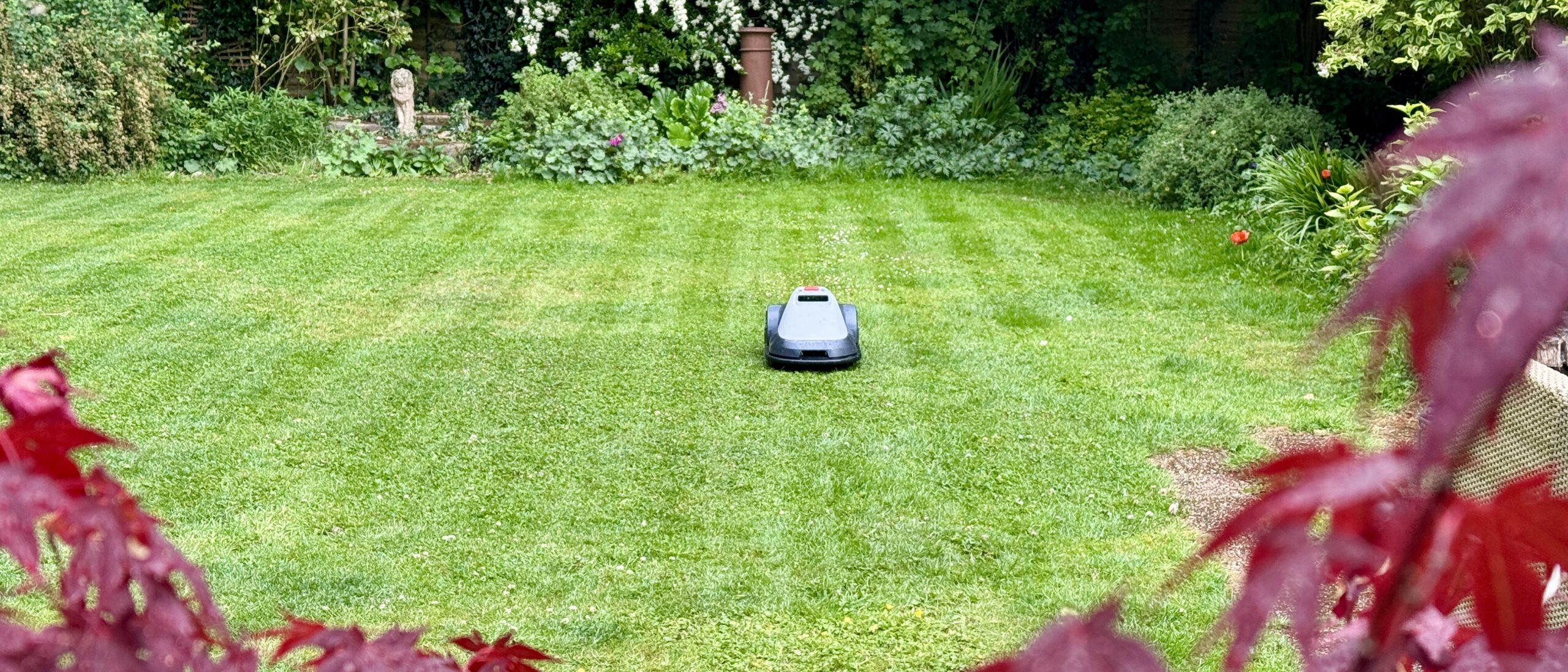 Eufy E15 robot lawn mower mowing in neat stripes on reviewer's lawn