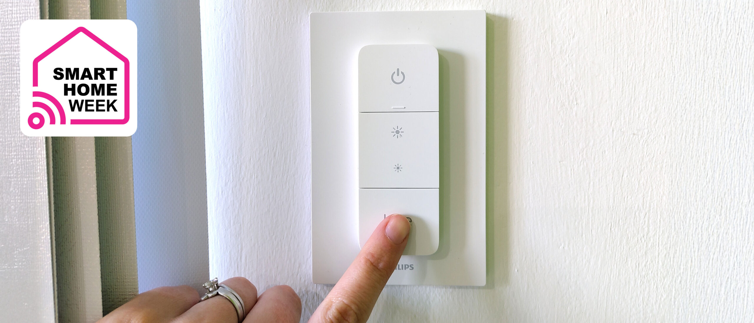 Woman's hand pressing Philips Hue Dimmer Switch on wall