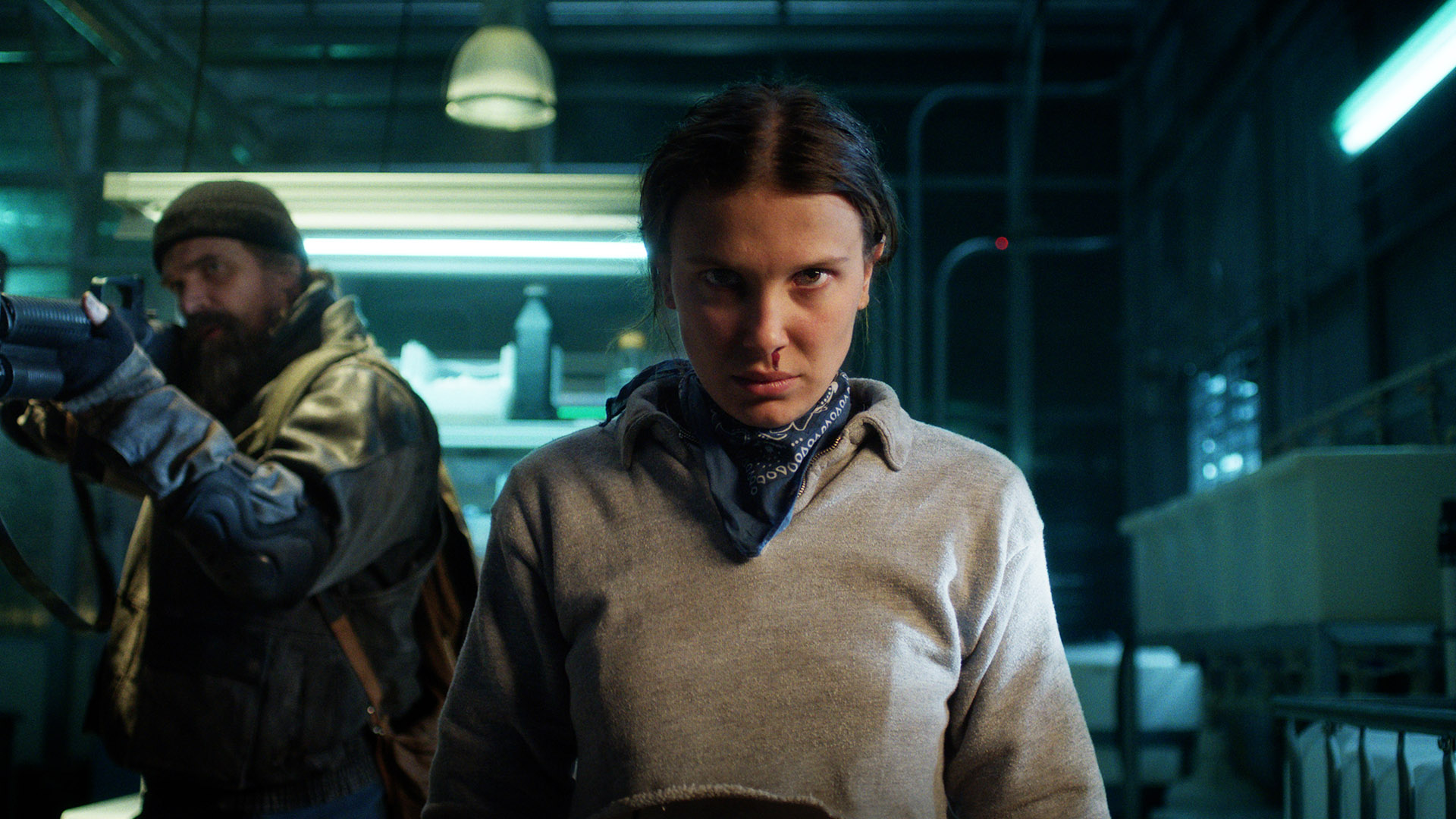 Eleven standing in a room with Hopper to her right holding a shotgun in Stranger Things season 5