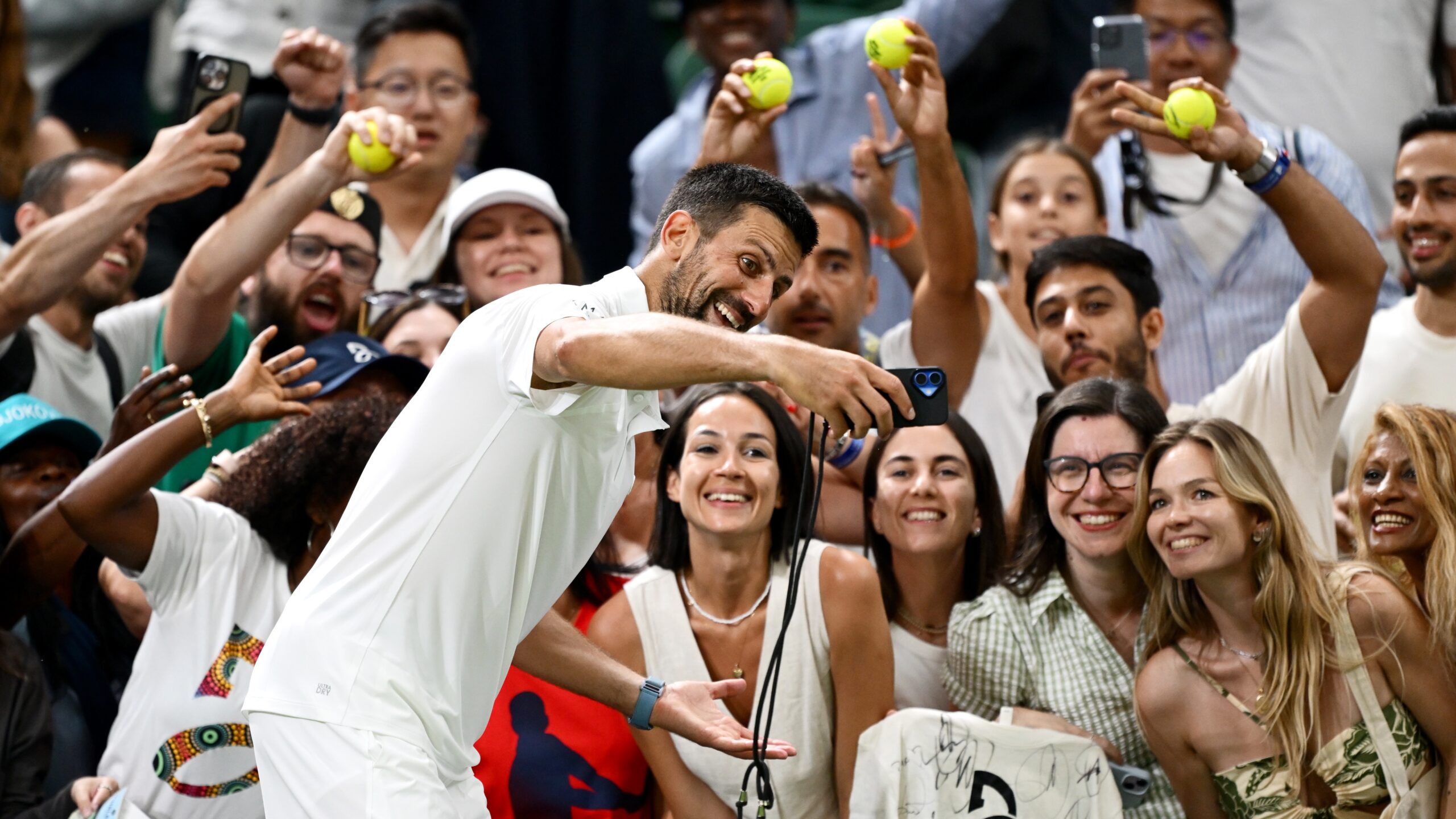 Novak Djokovic taking a selfie with fans at Wimbledon.