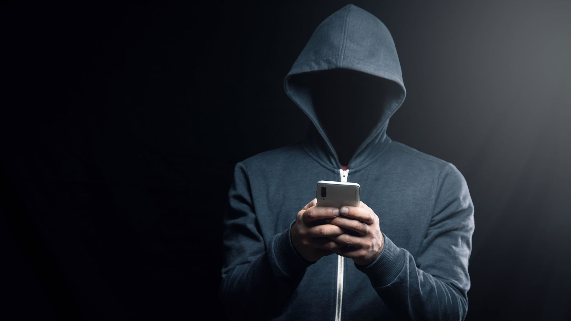 A dark figure in a hoodie representing a hacker.