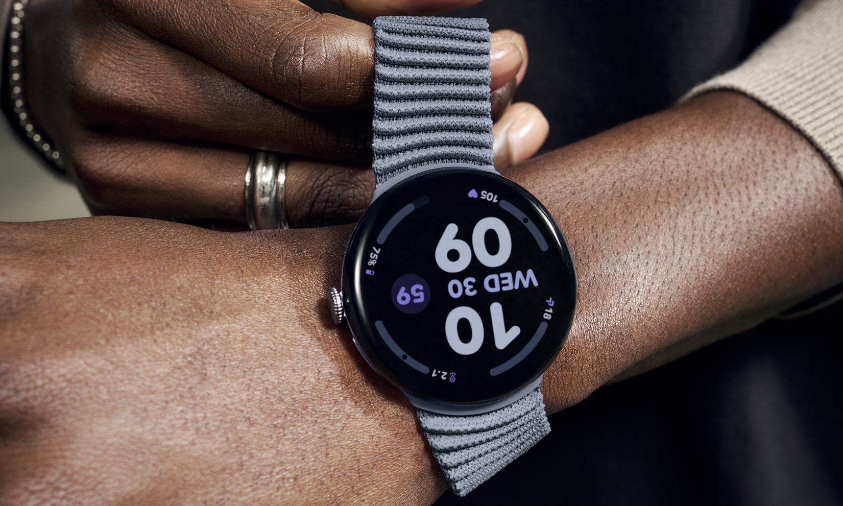 A hand pulling the stretchable strap on the Pixel Watch 4