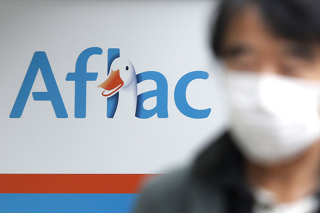 aflac's logo in the background, with someone wearing a mask in the foreground.